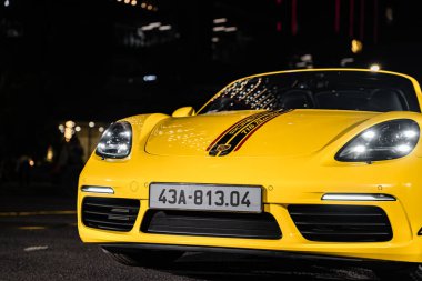 Hanoi, Vietnam - 26 Haziran 2024: Hanoi, Vietnam 'da sokağa park edilmiş sarı bir Porsche 718 Boxster. Porsche, 1931 'de kurulan yüksek performanslı spor arabalar konusunda uzman bir Alman otomobil üreticisi..