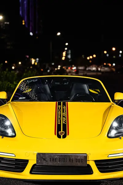 Hanoi, Vietnam - 26 Haziran 2024: Hanoi, Vietnam 'da sokağa park edilmiş sarı bir Porsche 718 Boxster. Porsche, 1931 'de kurulan yüksek performanslı spor arabalar konusunda uzman bir Alman otomobil üreticisi..