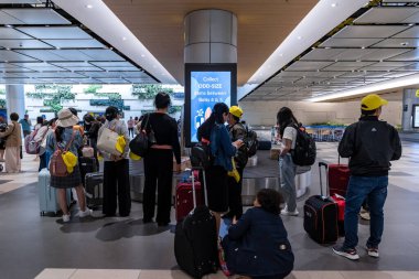 Singapur - 13 Haziran 2024: Verimli Seyahat: Yolcular, Changi Havaalanı, Singapur Terminali, Changi Havaalanı 'ndaki yolculuklarına hazır olarak, havaalanı taşıma bandından bavullarını alıyorlar