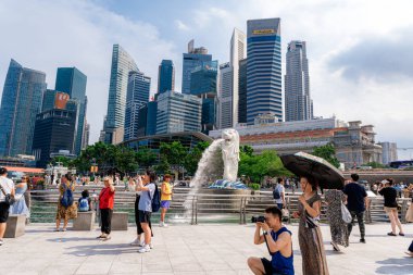 Singapur - 13 Haziran 2024: Merlion Parkı 'ndaki Merlion Fountain ve Singapur şehir silueti sabah mavi gökyüzü ile. Merlion Fountain, Singapur 'un en ünlü turistik yerlerinden biridir. Seyahat kavramı