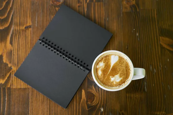 cup of coffee and a notebook on a wooden background