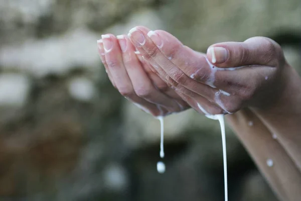hands washing water from a glass