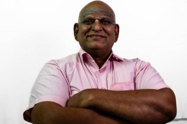 Güney Hintli yaşlı ve kel bir adam beyaz bir arka planda ellerini kavuşturuyor..