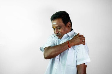 Sağ omzunu ağrı içinde tutuyor. Beyaz bir gömlek ve dhoti giyiyor.