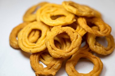 Namkeen (baharatlı) tereyağıyla yapılmış gevrek, altın sarısı bir murukku 'nun yakın plan çekimi.