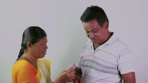 这段视频讲的是一个南方印第安人的妻子在数钱 而丈夫在简单的背景下给钱 — 图库视频影像