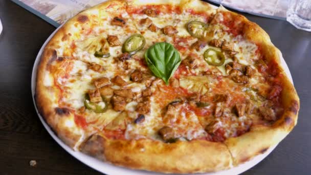 このビデオは チーズトマトソースとグリーンチリのトップアップ葉でいっぱいのイタリアのチキンピザについてです — ストック動画