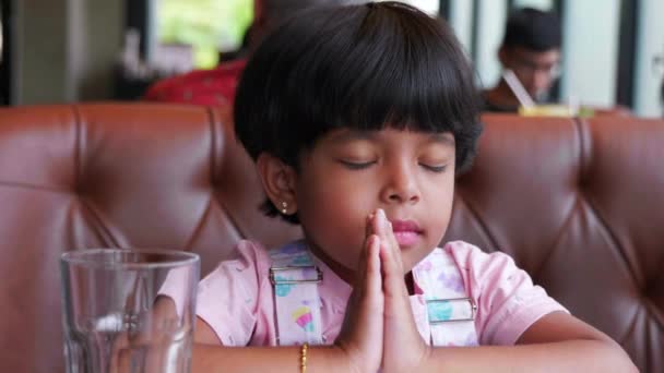 这段视频是关于女孩在饭前在宾馆里祈祷 穿着粉色衣服在前面的水杯里 她闭上眼睛 — 图库视频影像
