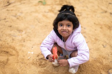 Küçük bir kız çamurda oynarken eğleniyor. Gülüyor, gülümsüyor ve hayatının en güzel zamanlarını geçiriyor gibi görünüyor..