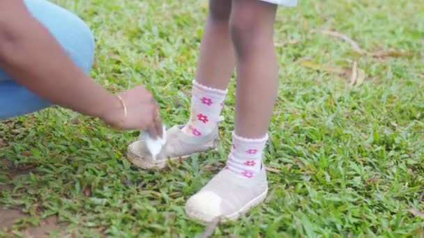 このビデオは公園で子供の汚れた靴下を掃除している母親を示しています 母親は我慢強く愛情がある — ストック動画