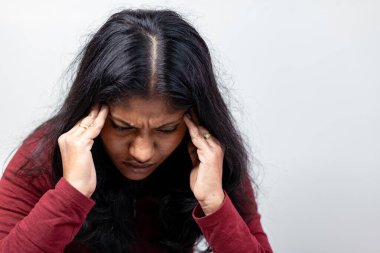 20 'li ya da 30' lu yaşlarda, elleri alnında aşağıya bakan üzgün bir kadının yakın çekimi.