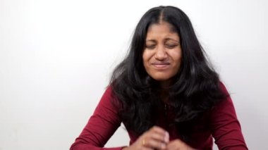 20 'li ya da 30' lu yaşlarda, elleri alnında aşağıya bakan üzgün bir kadının yakın çekimi.