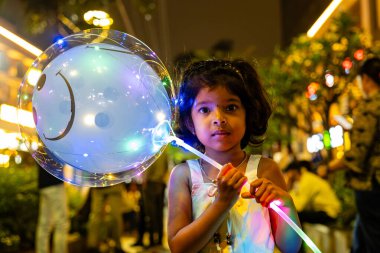 Bir çocuk sokakta elinde bir balon tutuyor.