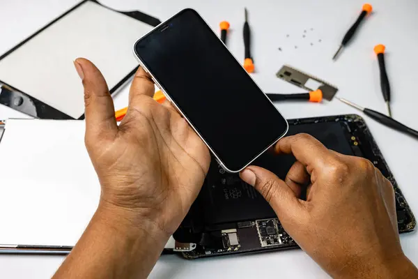 skilled technician is carefully repairing a mobile and tablet with a variety of tool kits