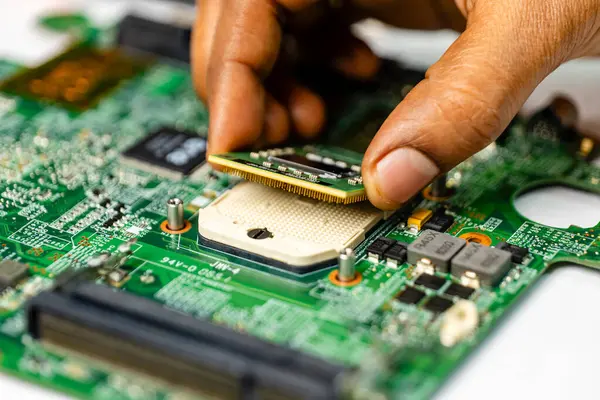 technician meticulously repairs a laptop motherboard using a variety of specialized tools