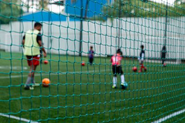 Kararlı genç bir kız futbol yeteneklerini güneşten ıslanmış bir alanda bilemeye çalışıyor. Korumalı ağın altında salya sümük ve tekme atarken dikkati hiç dağılmıyor.