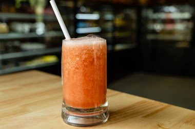 Yakut kırmızısı karpuz suyuyla dolup taşan soğuk bir camın fotorealistik görüntüsü.