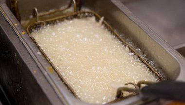 Sıcak yağın paslanmaz bir tavada güçlü bir şekilde kaynadığı yakın çekim görüntüsü, seçici bir odak noktası var.