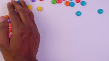 Bu video beyaz arka planda kelime eğlencesi şeklinde renkli şekerlemeleri elle ortaya çıkarmakla ilgili.