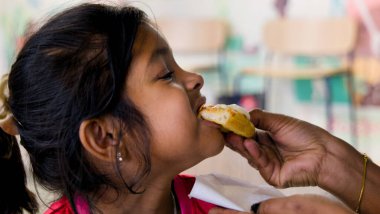 Fast food kafeteryasında oturmuş lezzetli bir pizza dilimini ısıran genç bir kadının yakın plan fotoğrafı.
