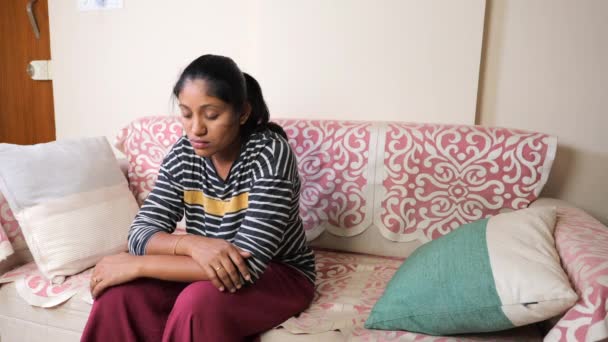 ある若いインド人女性がソファーに一人で座り 深く考えている 彼女の表現は熟考的で 恐らく心配しているか ストレスを感じている — ストック動画