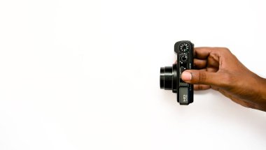 stock photo depicts a hand gripping a sleek digital camera, set against a crisp white background. The clean composition allows for easy integration of text or design elements. clipart