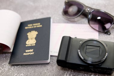 Bu fotoğraf Hindistan pasaportlu fotoğraf makinesi ve gri arka plan seyahat konseptindeki güneş gözlüğü hakkında.