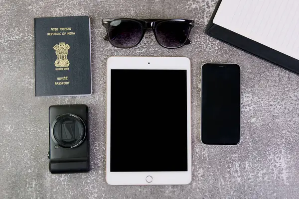stock image This stock photo showcases a flat lay arrangement of travel must-haves, including a tablet, passport, sunglasses, and a smartphone