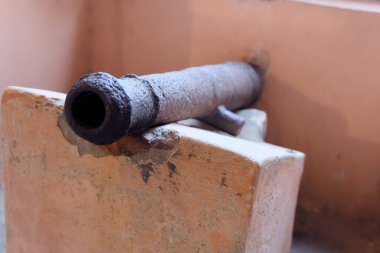 Eski bir top taş bir duvarda duruyor, tarihi ve askeri stratejiyi çağrıştırıyor. Tarihsel bağlamlar için mükemmel.