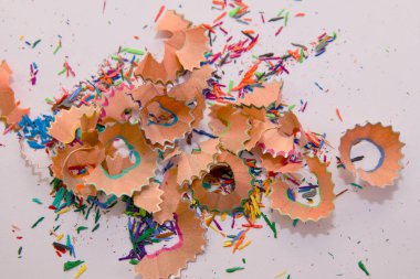 Beyaz bir yüzeye saçılmış renkli kalem talaşlarının yakın çekimi, canlı renkler ve yaratıcı karmaşa sergiliyor..