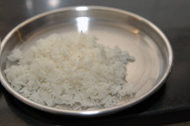 Parlak paslanmaz çelik bir tabakta servis edilen pişmiş beyaz pirincin yakın plan görüntüsü yenmeye hazır..