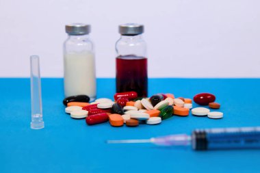 Bir dizi ilaç şişesi, ilaç paketleri ve şırınga, sağlık hizmetleri ve ilaç tedavilerini işaret ediyor..