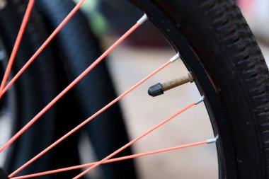 Parlak kırmızı jantları ve parlak kapakçık sapı olan siyah bir bisiklet lastiğinin yakın çekimi.