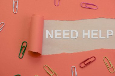 Renkli ataçlarla çevrili yırtık kağıtlardan yardım isteyen bir mesaj çıkıyor.