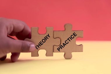 Elinde teori ve pratik etiketli iki yapboz parçası tutan kişi