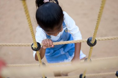 İp engeli parkurunda ilerleyen azimli genç kız, zirveye ulaşmaya odaklanmış..