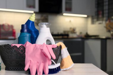Mutfak yüzeyine yerleştirilmiş eldivenler ve deterjanlar da dahil olmak üzere bir temizlik malzemesi koleksiyonu. Görüntü, çağdaş bir mutfak ortamında temizlik ve organizasyon taşır..