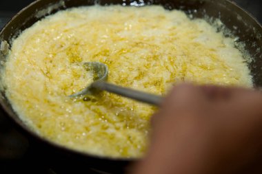 Bir tavada cızırdayan Ghee 'nin yakın çekimi, lezzetli bir altın doku yaratıyor..