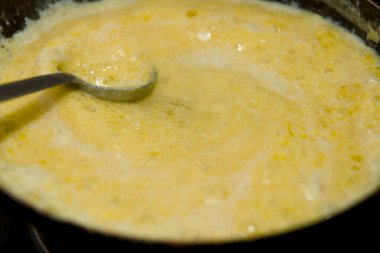 Kalın, kabarcıklı, altın karışımı Ghee tavada yemek pişiriyor, lezzetli bir yemek dokusu yaratıyor..