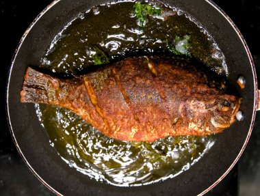 Lezzetli bir yemeğe hazır, sıcak yağda cızırdayan mükemmel baharatlı bir balık..