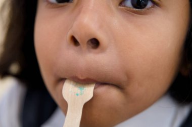 Close-up of a child savoring the last bits of a sweet treat, capturing the joy and mess of childhood indulgences. clipart