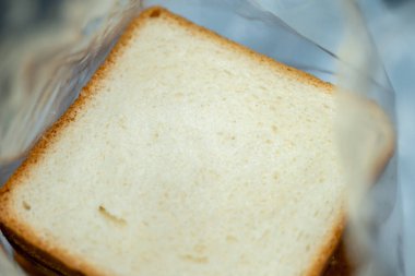 Plastiğe sarılı taze bir ekmek dilimi, sandviç ya da atıştırmaya hazır. Yumuşak doku ve altın kabuk.