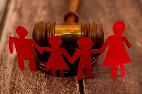 Tokmağın önünde kırmızı kağıt aile zinciri. Çocuk velayeti, boşanma ve evlat edinme hukuki kavramları.