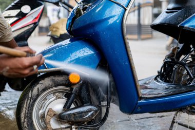 Ferahlatıcı durulama! Mavi bir scooter, güneş altında ışıl ışıl parlayan bir su jetiyle eksiksiz bir temizlik yaptırır..