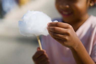 Güneşli bir günde pamuk şekerin tadını çıkaran bir çocuk..