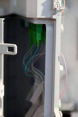 Birbirine bağlı yeşil ve temiz plastik kaplamalı kablolar inşaat alanındaki açık bir kutudan görülebiliyor. Parlak güneş ışığıyla yıkanmış..