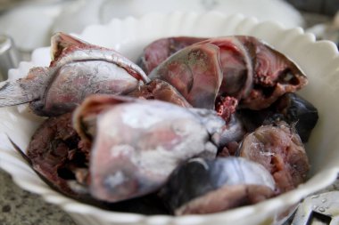 Kırsal bir mutfak masasında seramik bir kaseye yerleştirilmiş parlak, taze bir balığın yakın plan fotoğrafı..