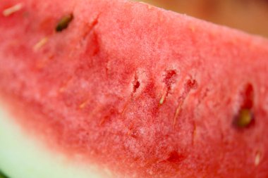 Sulu bir karpuz diliminin yakın plan fotoğrafı. Canlı kırmızı et ve siyah tohumlarını gösteriyor..