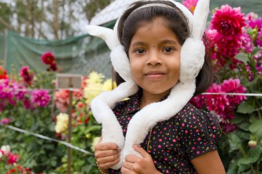 Beyaz tavşan kulağı takan, tüylü kulaklık takan, büyüleyici ve masum bir kız. Neşeli kıyafeti ve neşeli ifadesi