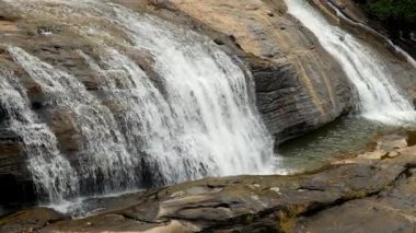 Su engebeli taşların üzerinden zarif bir şekilde akar ve bu doğal ortamda sakin bir atmosfer yaratır..